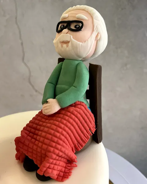 Abuelo en su sillón con manta roja de fondant